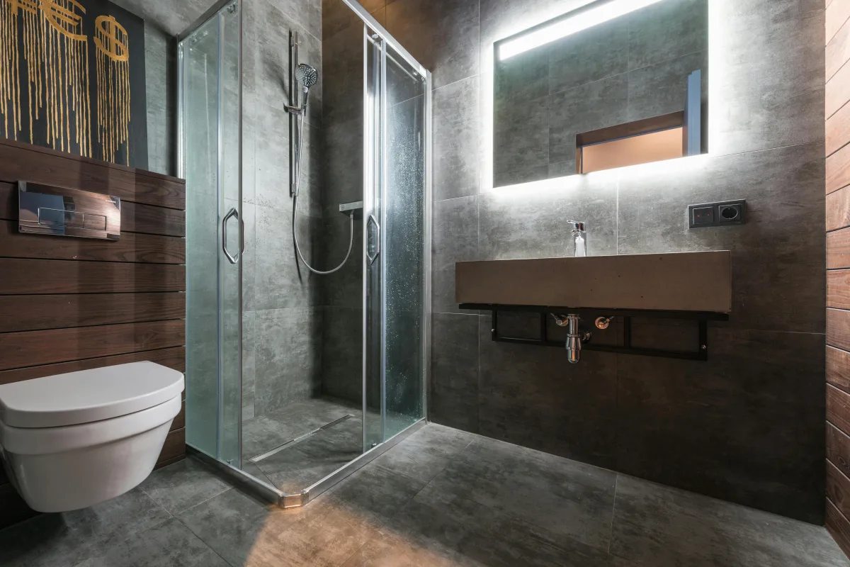 Vapeur montant dans une salle de bain bien éclairée avec une porte de douche vitrée.