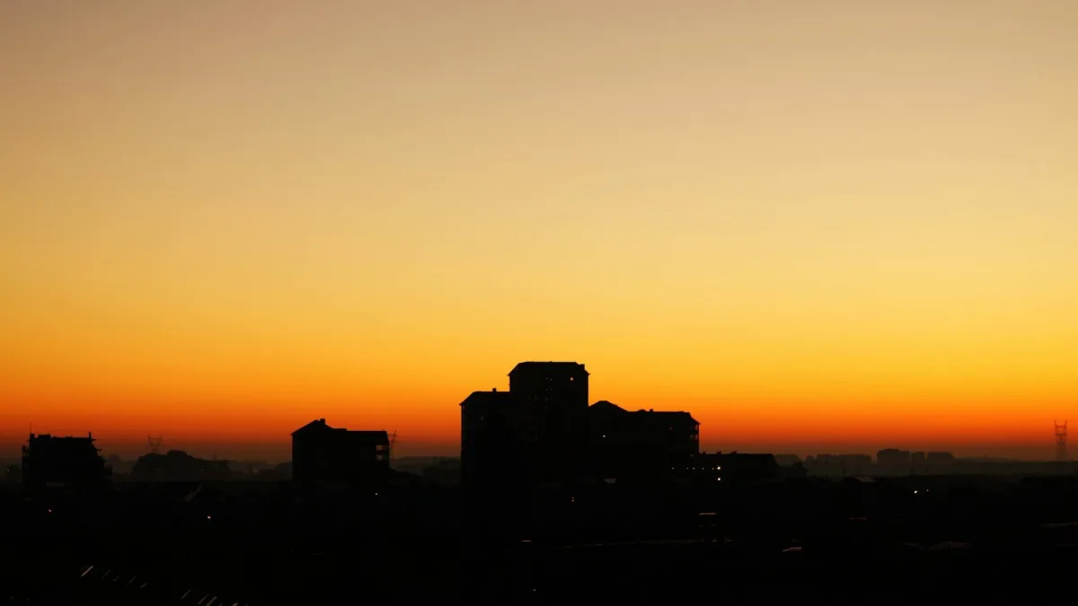 A composite image: sunrise over a city, with faint air-quality data overlay.
