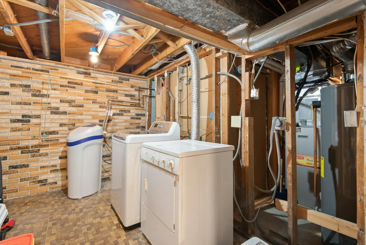A residential HRV unit in a basement utility room with frost on the outside vent and a Terrestream sensor on a wall.