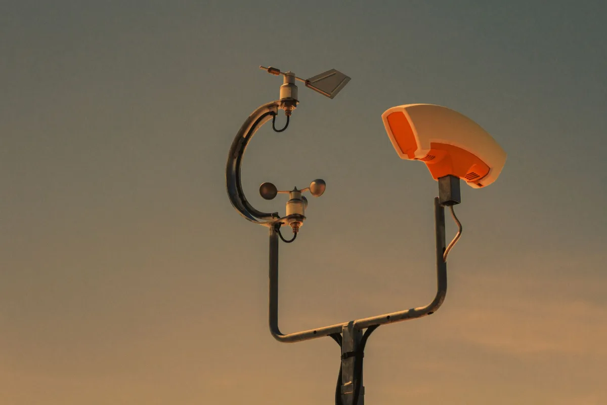 A government air-quality monitoring station with sampling tubes on a fenced rooftop.