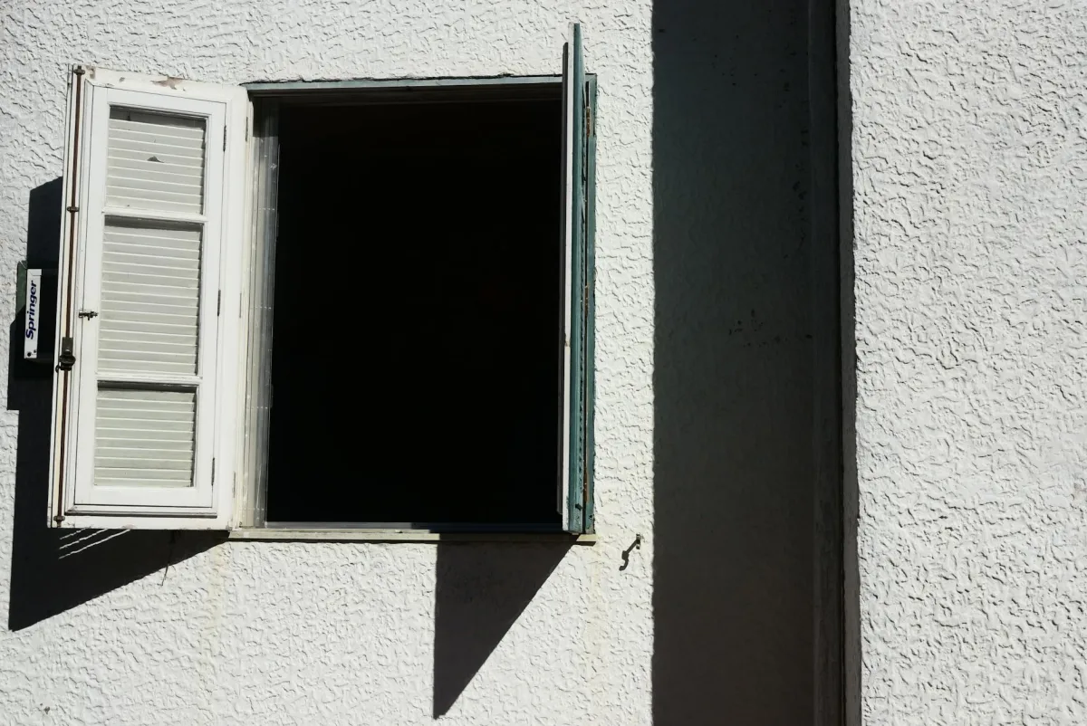 Un hogar en una tarde calurosa de verano con ventanas cerradas y el HVAC funcionando, un sensor Terrestream mostrando ozono interior bajo junto a una alerta de AirNow en un teléfono.