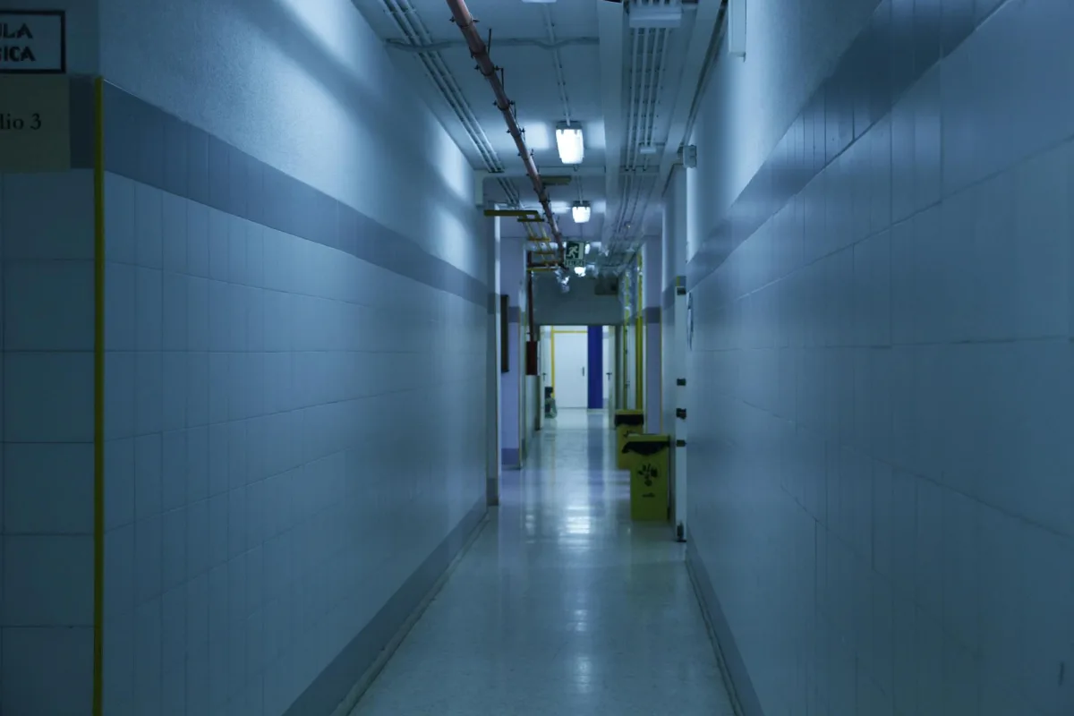 Un long couloir de bureau éclairé au néon avec des portes fermées des deux côtés.