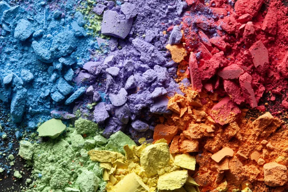 Crushed rainbow-coloured powder arranged in a spectrum, evoking fine respirable dust