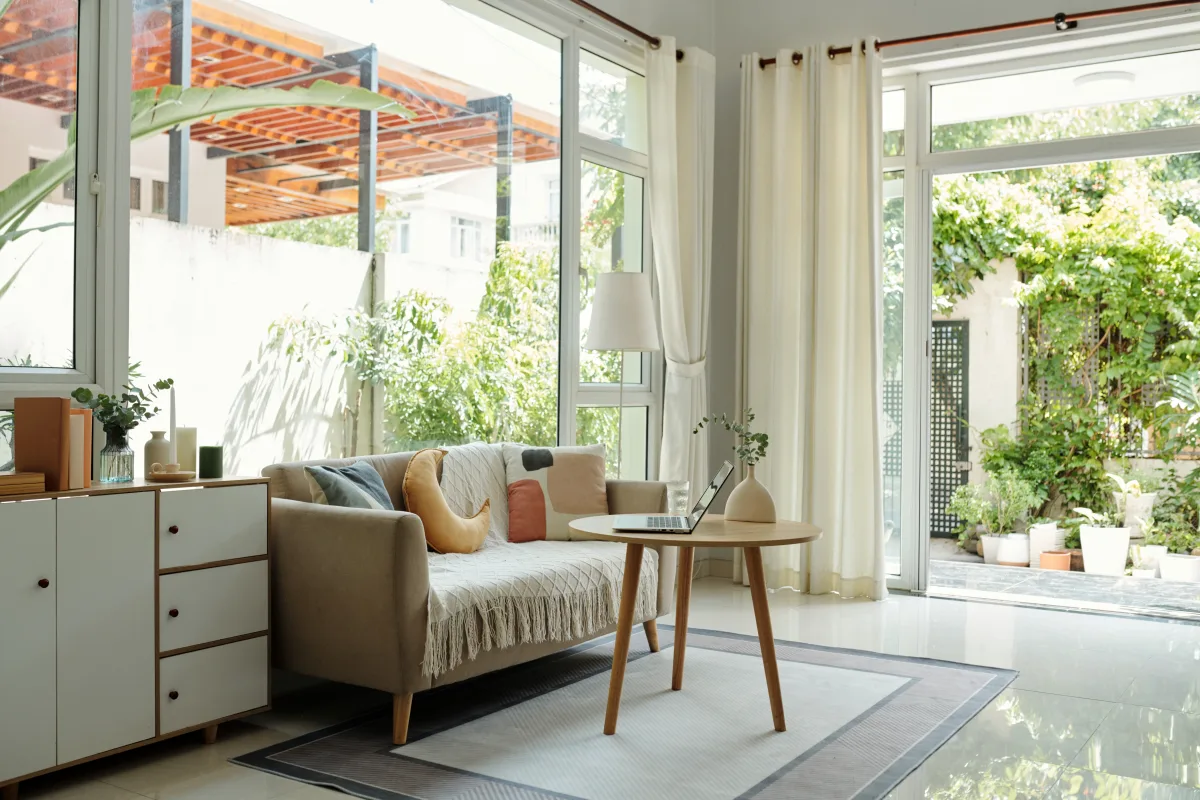 A bright living room with full-height patio doors wide open to a green garden