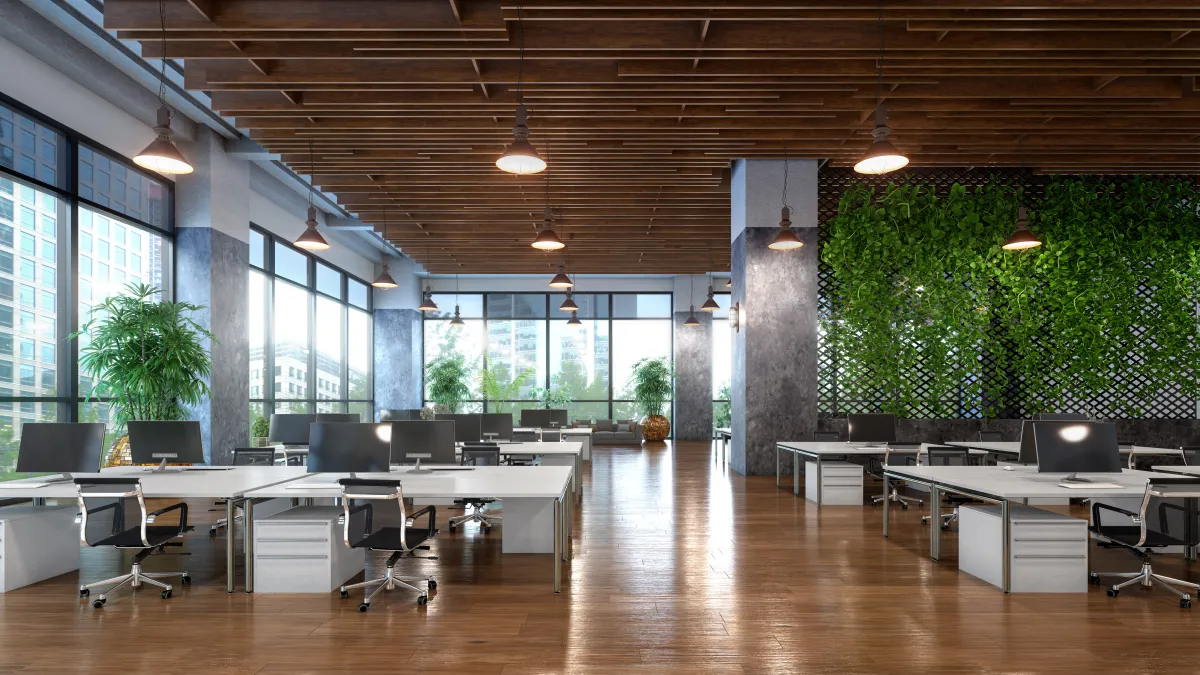 Open-plan office with desks, plants, and natural light